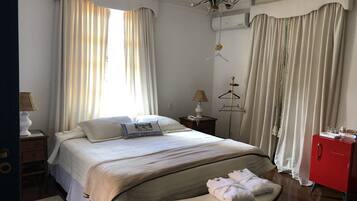 Une chambre d’hôtel comprenant un lit, une table de chevet avec une lampe, une armoire et un porte-manteau.