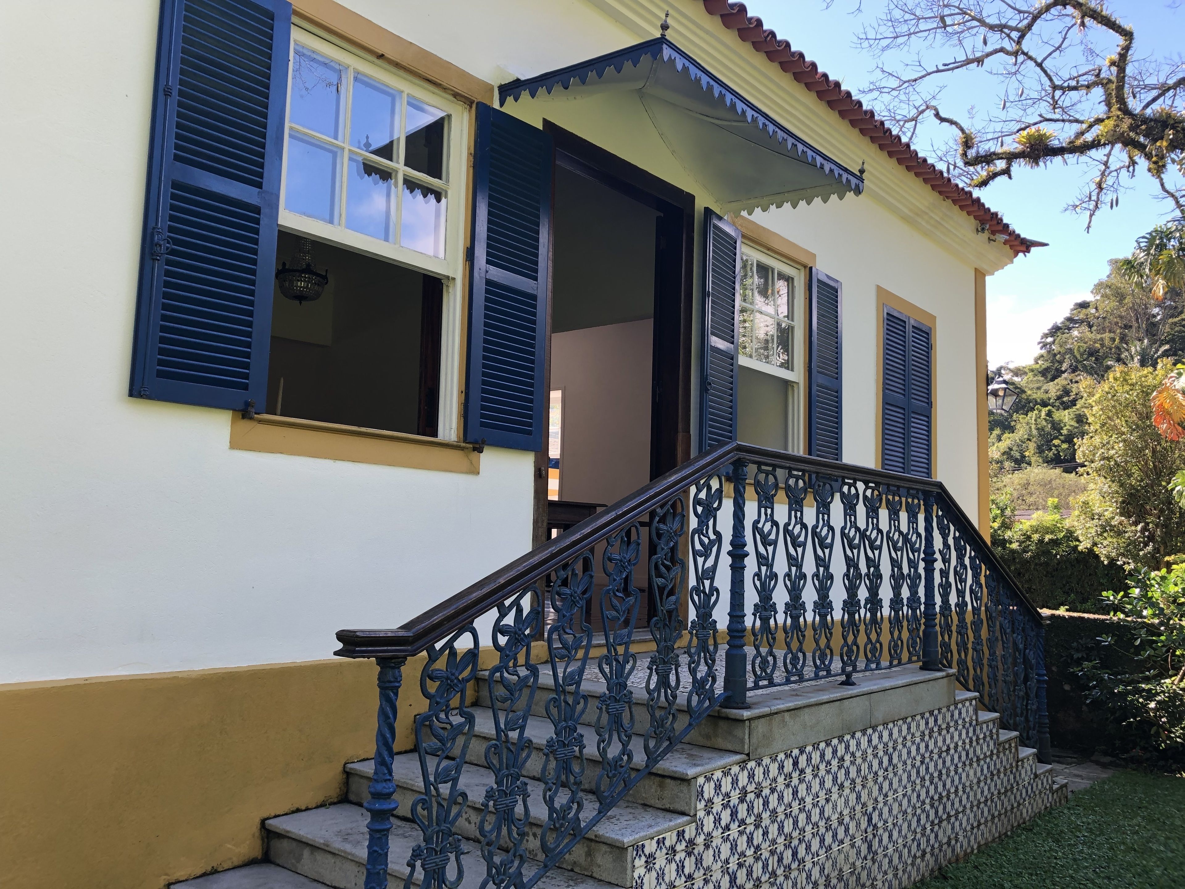 Un edificio con escaleras, contraventanas azules y un vestíbulo con baldosas.