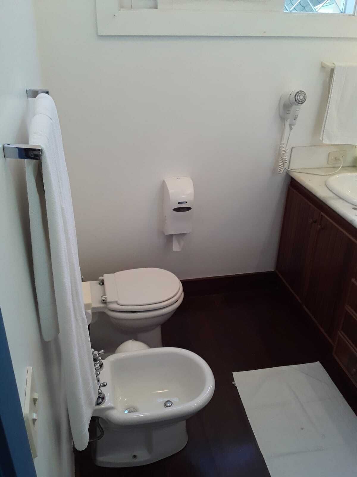 Een kleine badkamer met toilet, bidet en een handdoekrek.