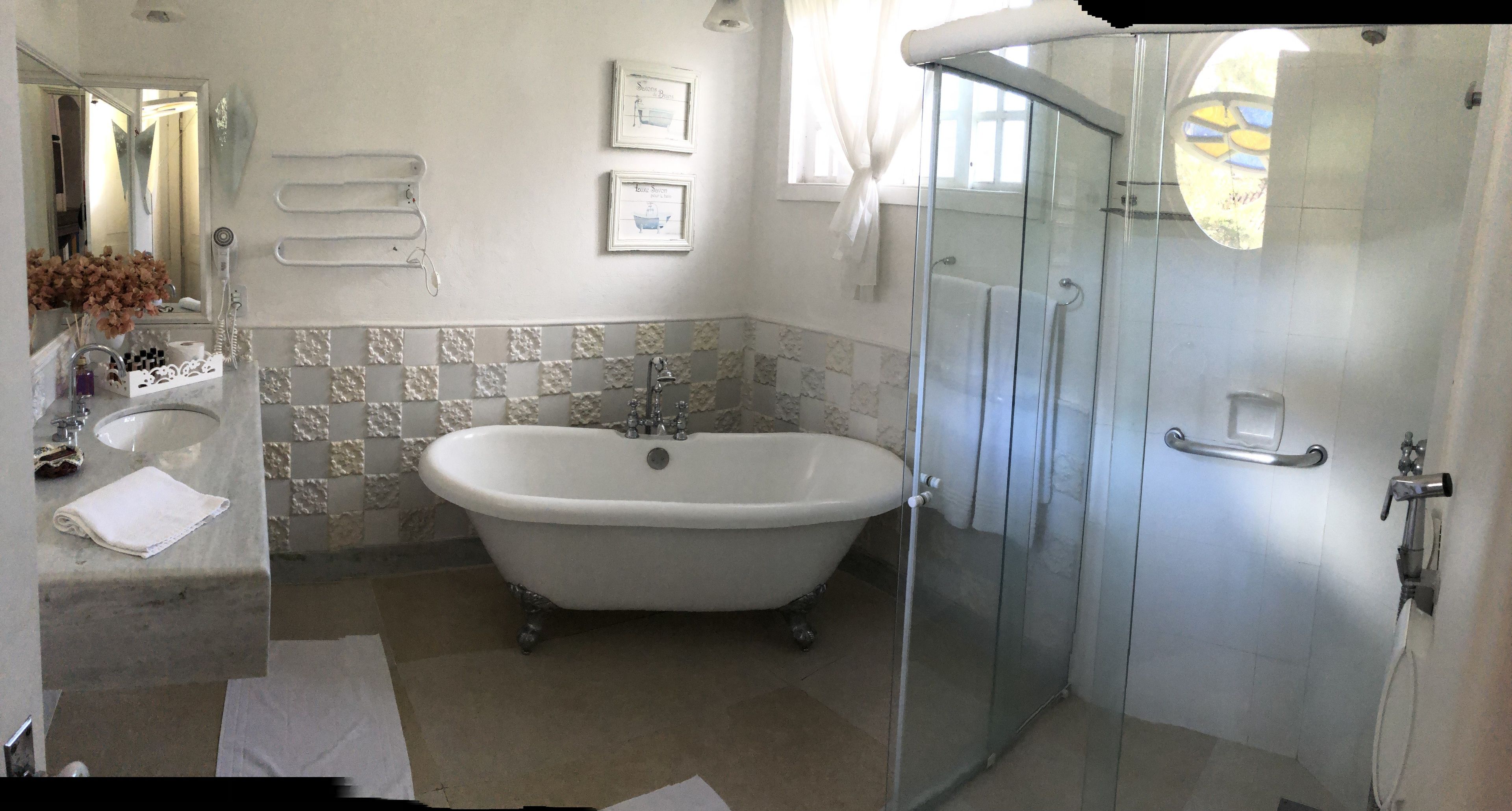 A bathroom with a freestanding bathtub, a glass-enclosed shower, a sink with a mirror, and decorative wall tiles.