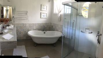 A bathroom with a freestanding bathtub, a glass-enclosed shower, a sink with a mirror, and decorative wall tiles.