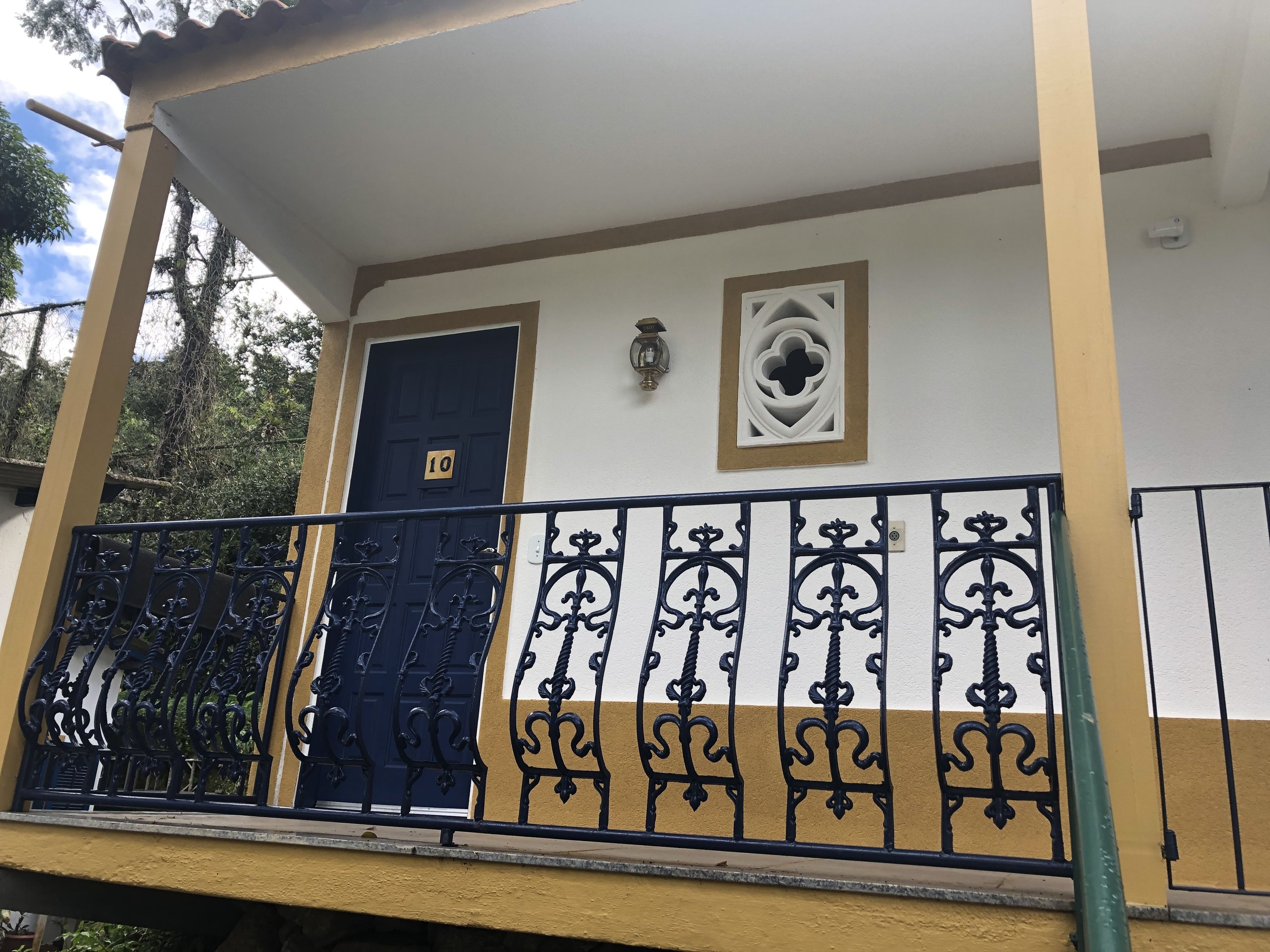 Un immeuble doté d’un balcon, d’une porte bleue portant le numéro 10 et d’une rampe en métal décorative.