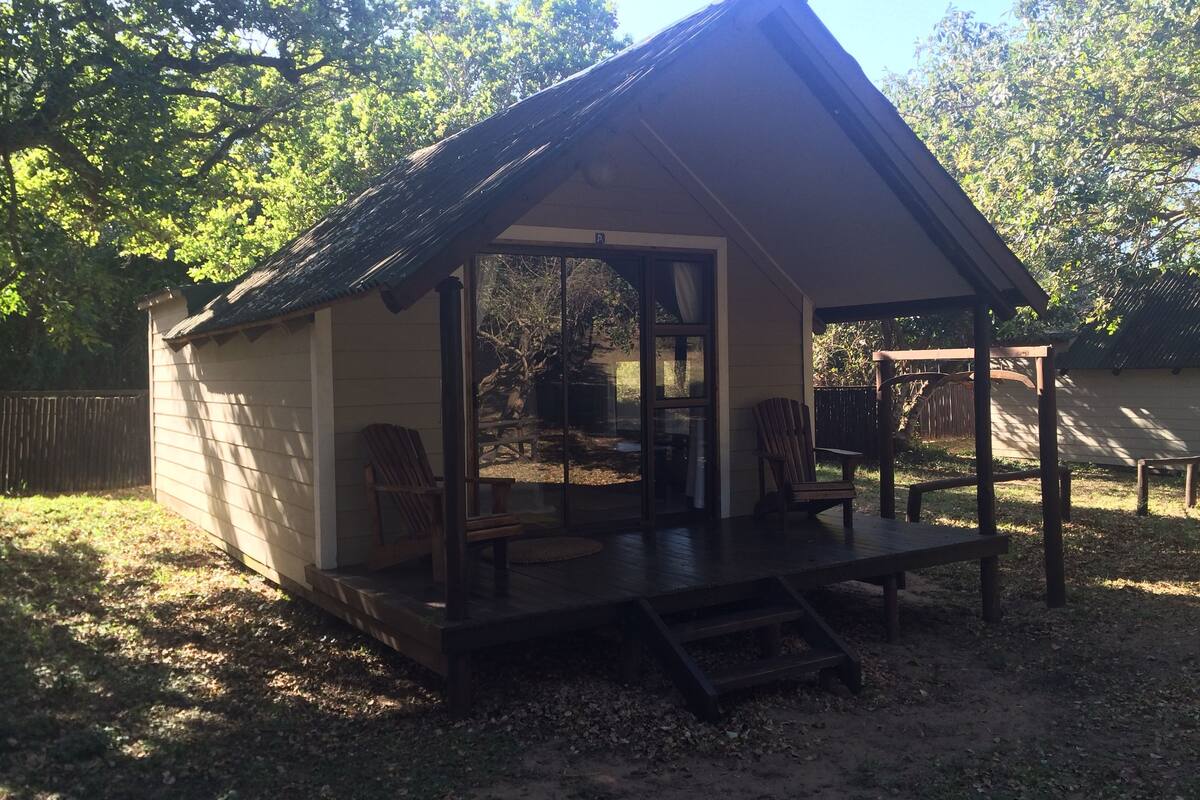 Une petite construction en bois d’un seul étage, dotée d’un porche, d’une porte-fenêtre coulissante et d’un espace de repos abrité.