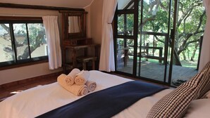 Een slaapkamer met een groot bed, een houten bureau en uitzicht op een terras.