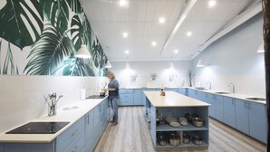 Een moderne keuken met blauwe kastjes, een centraal eiland en een grote wand met bladmotieven.