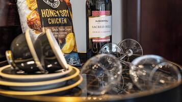 Une table avec un paquet de chips au poulet, sauce soja et miel, une bouteille de vin et plusieurs verres à vin.