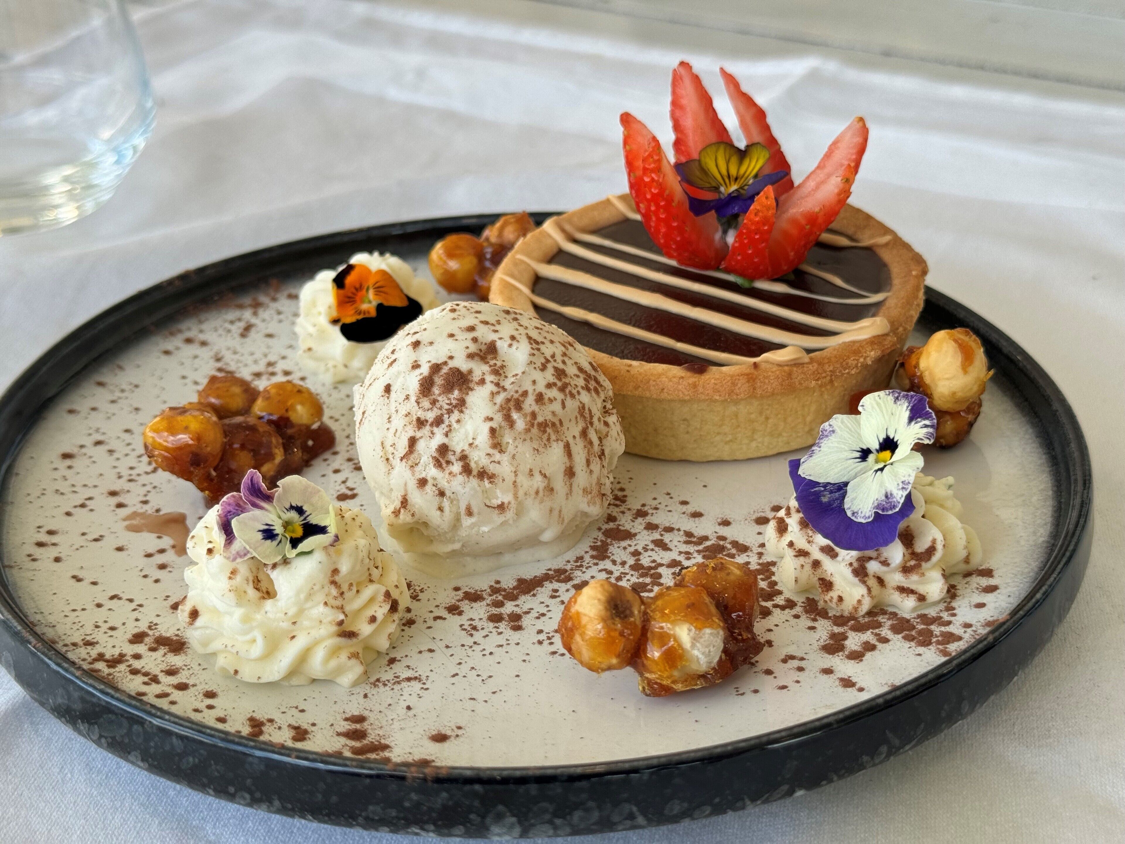 A dessert plate with a tart, ice cream, and nuts.