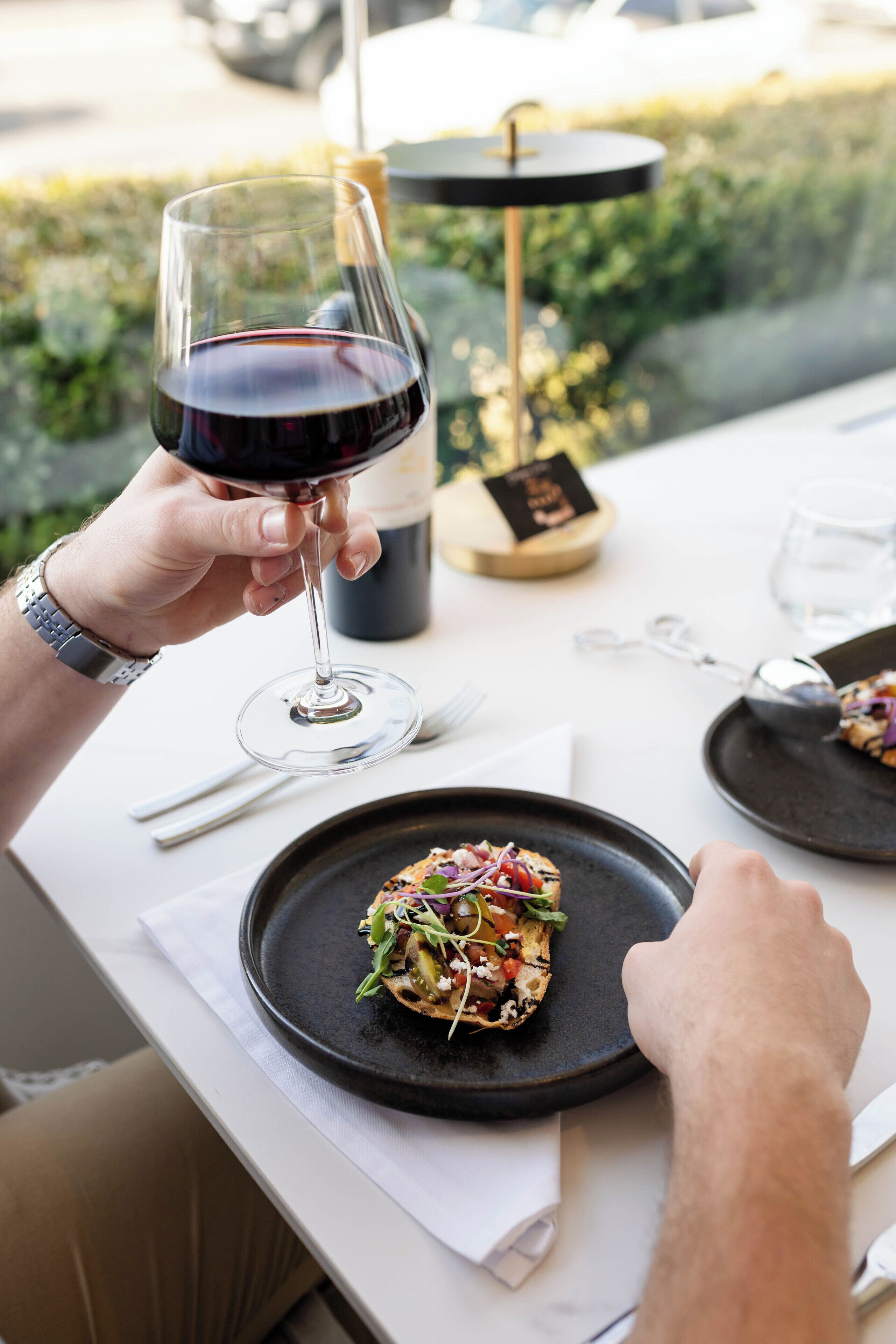 Une table à manger avec une assiette de nourriture, un verre à vin et une bouteille de vin.