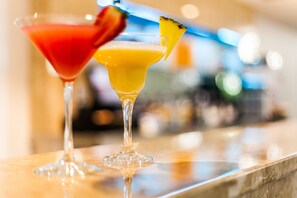 Two cocktails on a bar counter with a blurred background.