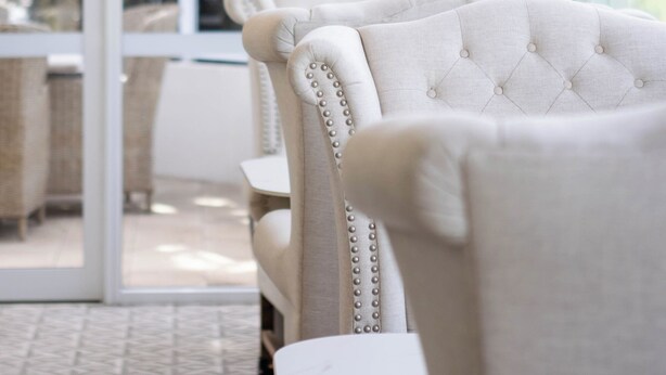 A room with a large window, a white upholstered chair, and a white vase with white flowers. - International Hotel Wagga Wagga (East Wagga Wagga)