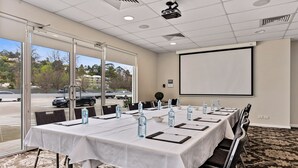 A conference room with a long table, chairs, water bottles, and a projector screen. - International Hotel Wagga Wagga (East Wagga Wagga)