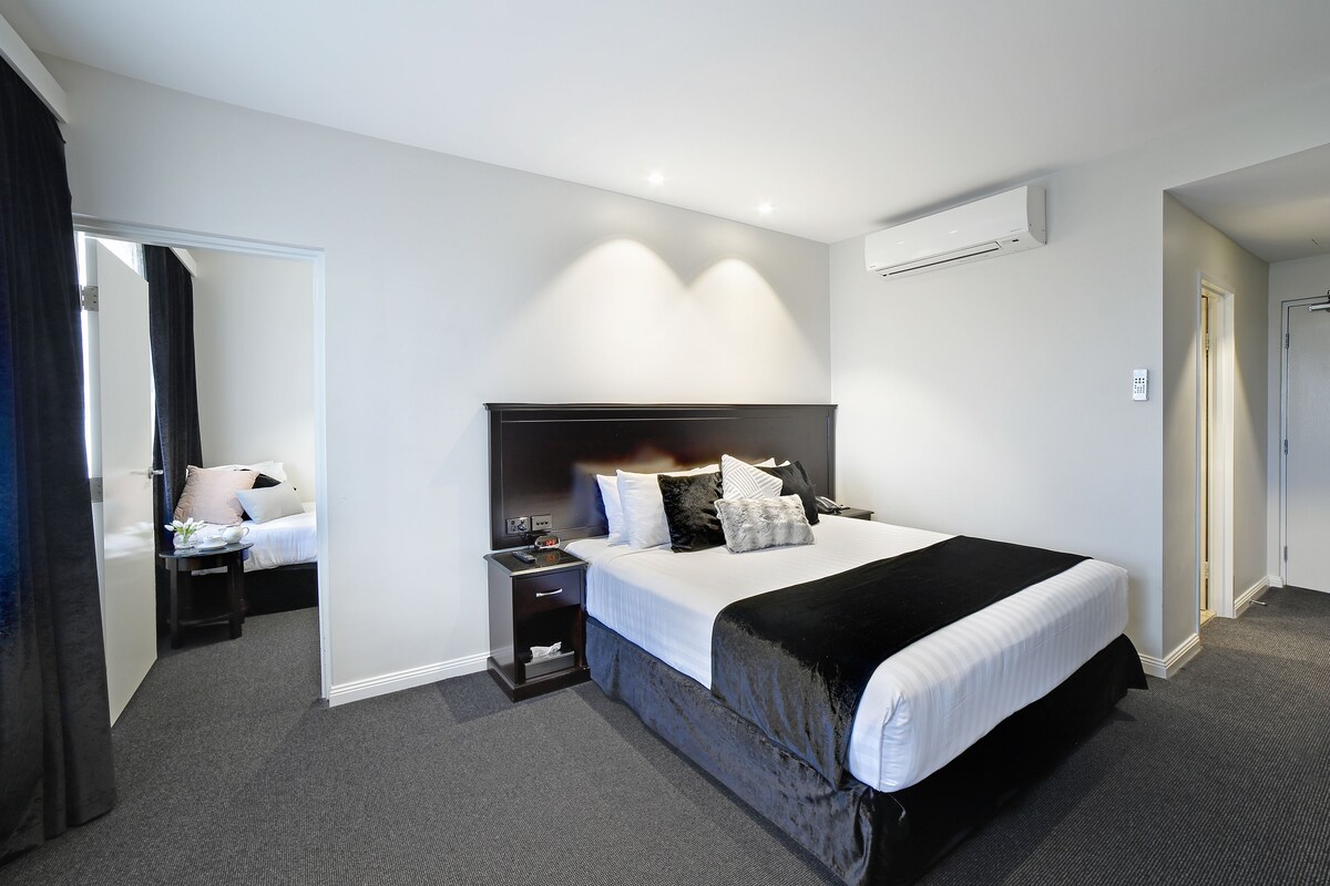 A hotel room with a large bed, bedside tables, a desk, and a chair.
