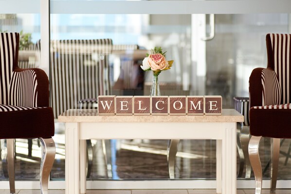 A reception desk with a 'WELCOME' sign and a vase with a flower. - International Hotel Wagga Wagga (East Wagga Wagga)