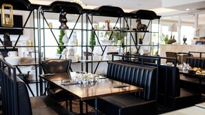 A restaurant with black leather booths and a wooden table set for dining. - International Hotel Wagga Wagga (East Wagga Wagga)