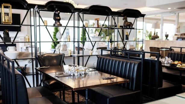 A restaurant with black leather booths and a wooden table set for dining. - International Hotel Wagga Wagga (East Wagga Wagga)