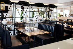 A restaurant with black leather booths and a wooden table set for dining. - International Hotel Wagga Wagga (East Wagga Wagga)