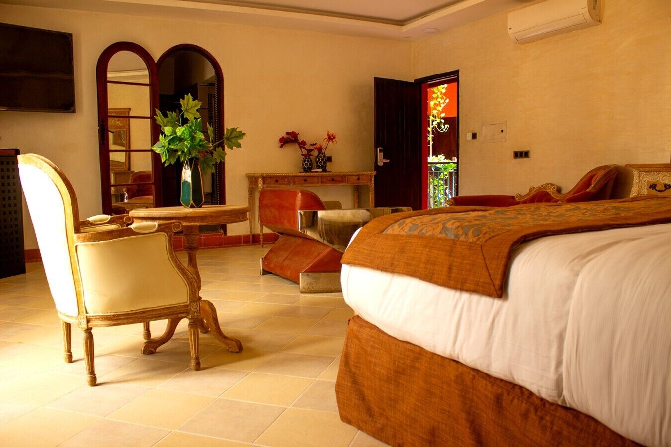 A bedroom with a large bed, a desk, a chair, and a mirror.