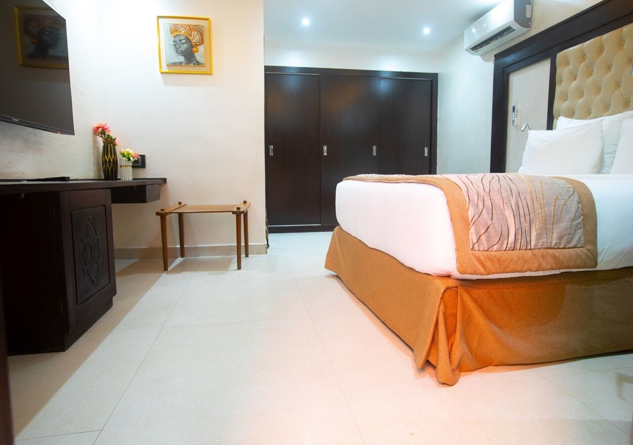 Habitación de hotel con cama, escritorio, silla, armario y una mesita.