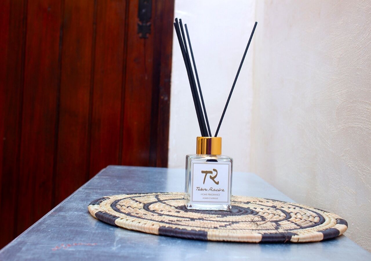 Una botella de Tabou Racis Home Fragrance sobre un posavasos tejido sobre una mesa.