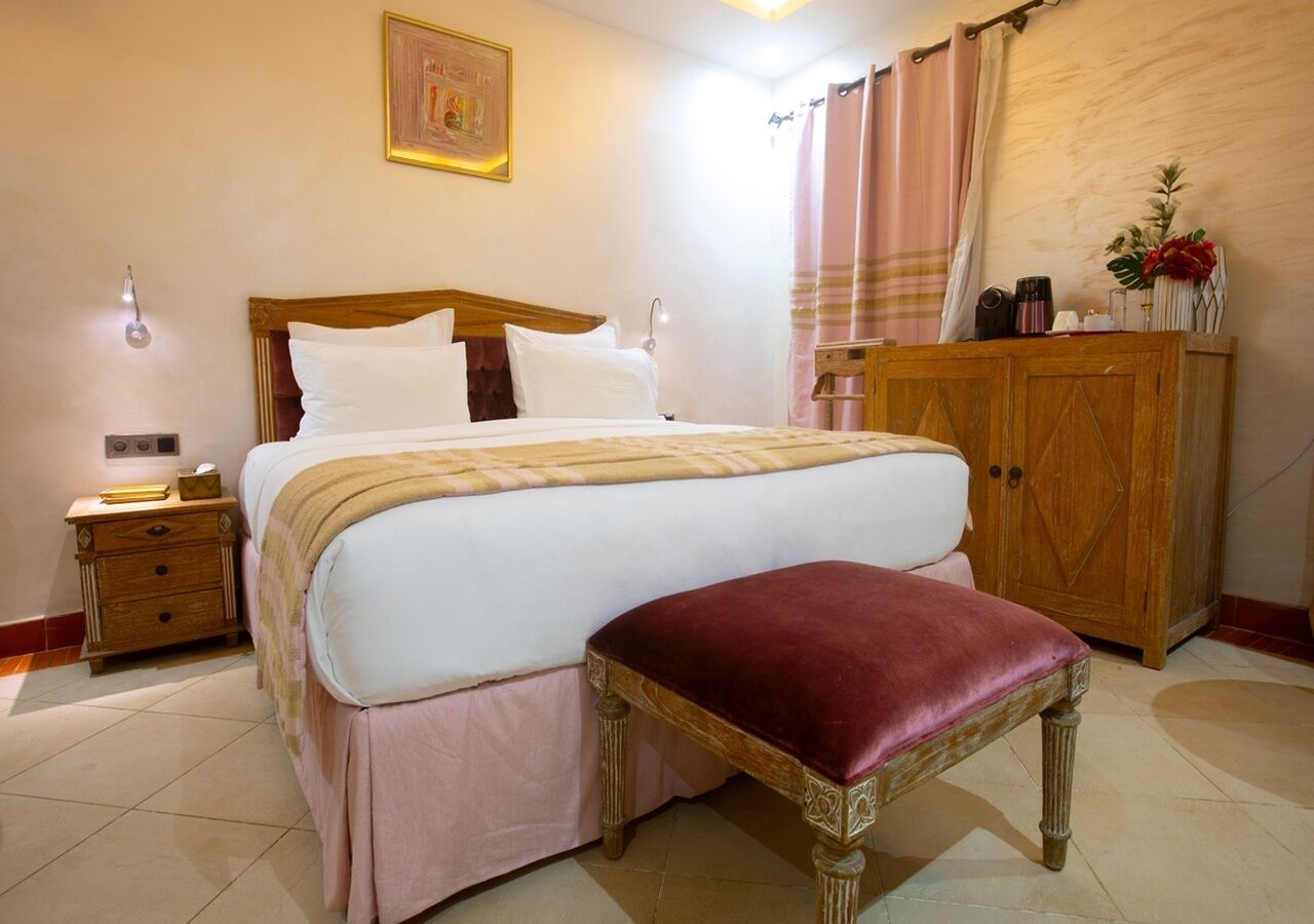 Une chambre à coucher avec un grand lit, une table de chevet en bois, une armoire en bois et un banc.