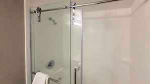 A glass-enclosed shower stall with a towel rack and a showerhead. - Motel 6 Jackson, TN (Jackson)