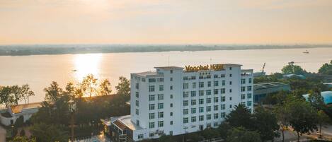 Un hotel con piscina, rodeado de árboles y una masa de agua.