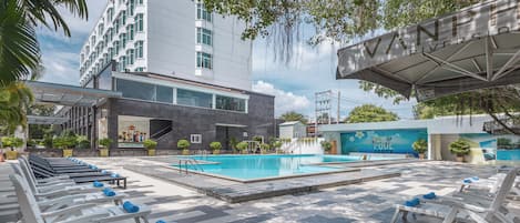 Una piscina al aire libre, sombrillas, sillones reclinables de piscina