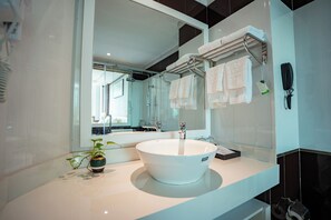 A modern bathroom with a large mirror, white sink, and towel rack.