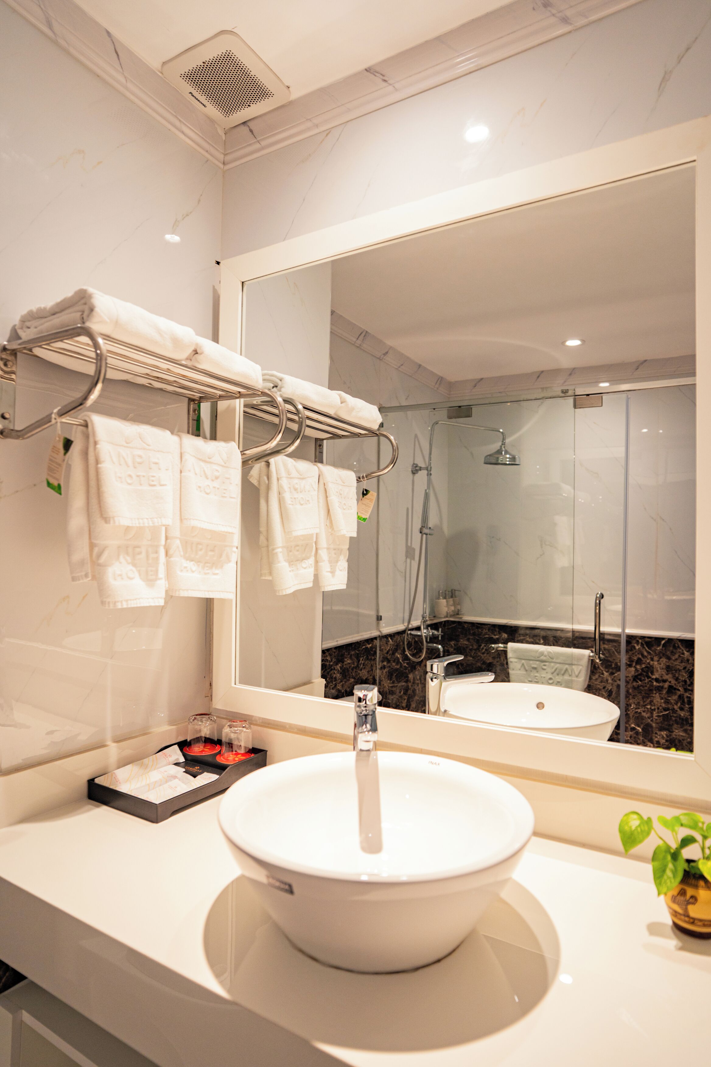A bathroom with a large mirror, a white sink, and a towel rack with folded towels.