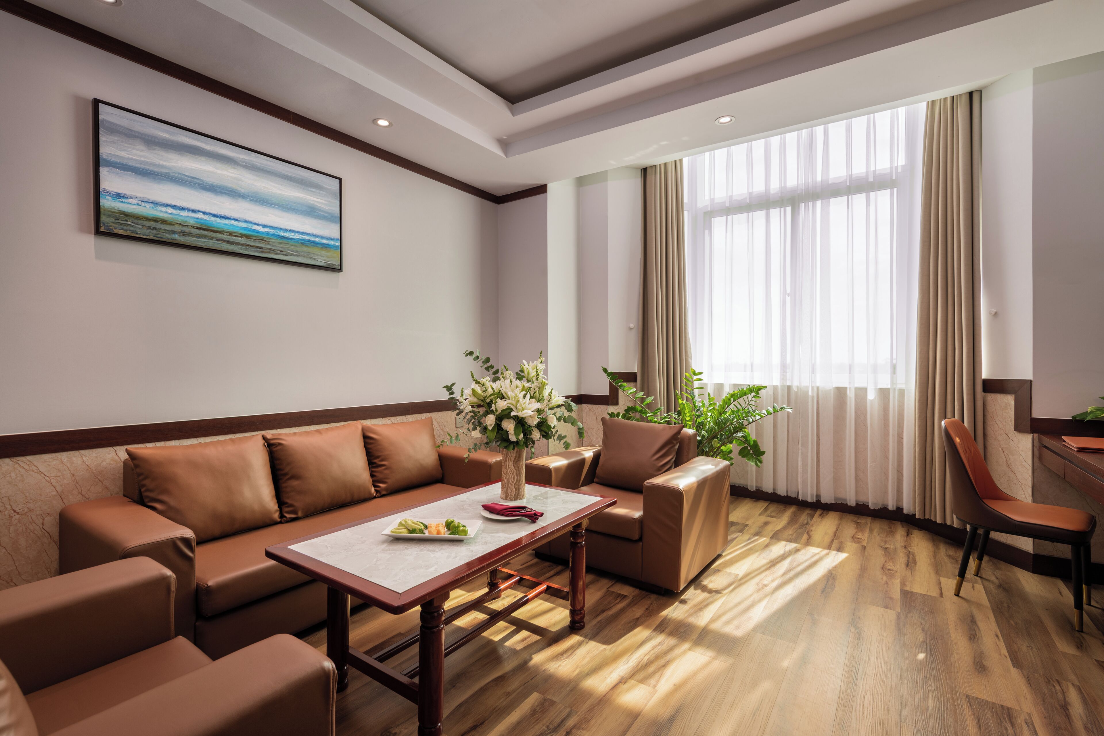 Una sala de estar moderna con un sofá, sillas, una mesa de centro y un cuadro en la pared.