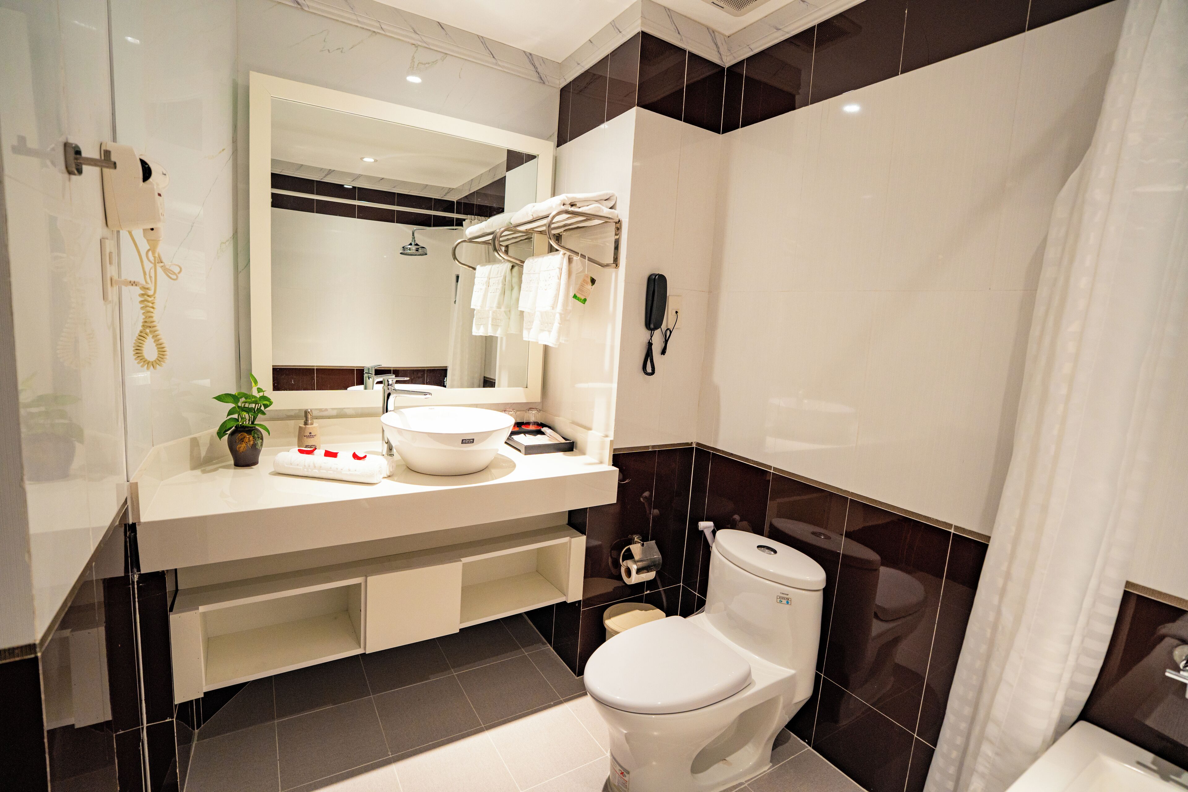 Un baño moderno con un lavamanos blanco, un inodoro, un espejo y un teléfono.