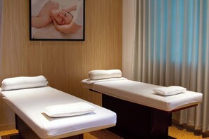 Two treatment beds in a room with wooden paneling and a framed picture on the wall.