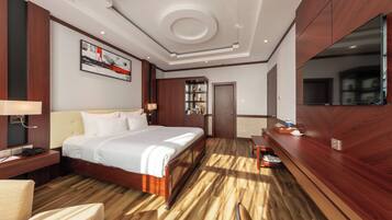 A hotel room with a large bed, bedside tables, a desk, a bookshelf, and a mirror.