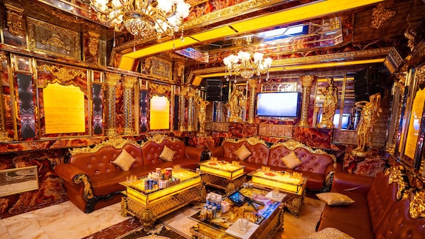 An opulent room with a plush red leather sofa, a gold-framed television, and ornate decor. - Van Phat Riverside Hotel (Can Tho)