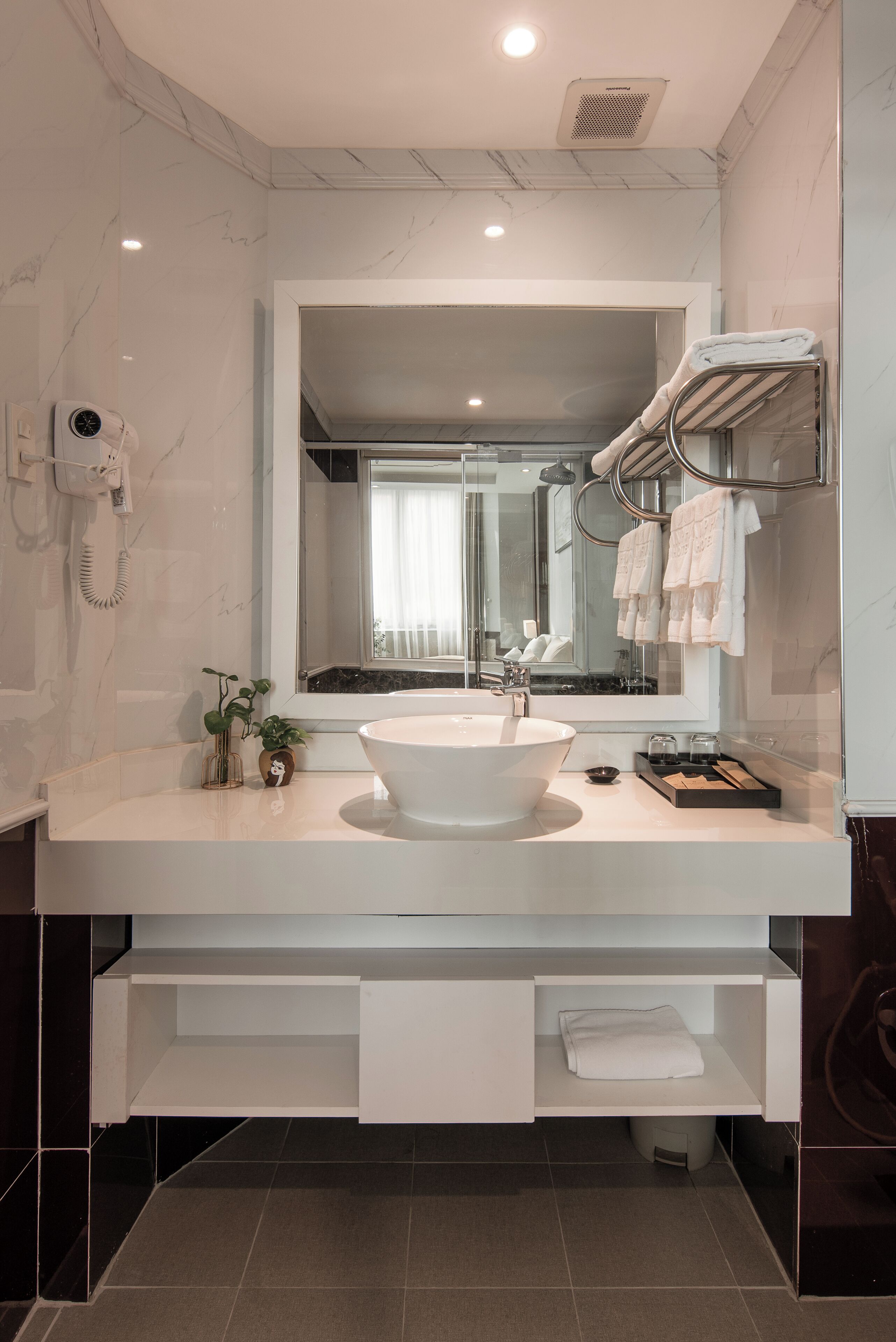 A modern bathroom with a large mirror, a white sink, and a towel rack.