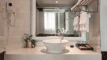 A modern bathroom with a large mirror, a white sink, and a towel rack.