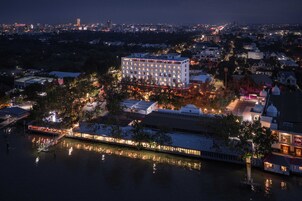 A multi-story hotel with a central courtyard, surrounded by a river and other buildings.