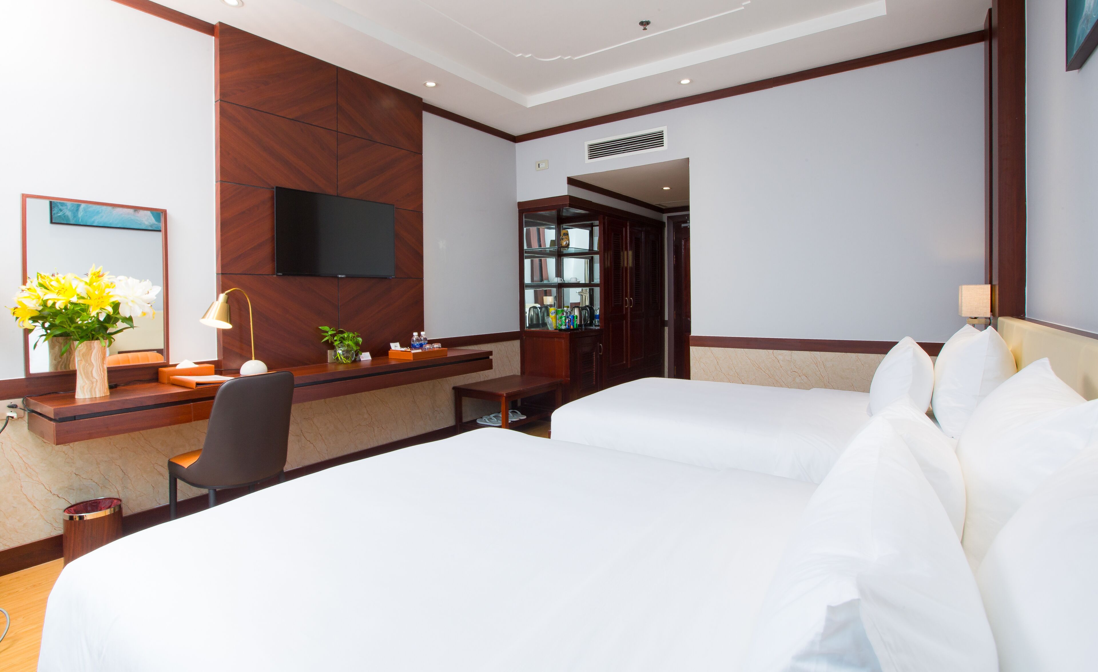 Une chambre d’hôtel équipée d’un bureau, de deux lits, d’une télévision et d’un miroir.