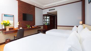 Une chambre d’hôtel équipée d’un bureau, de deux lits, d’une télévision et d’un miroir.