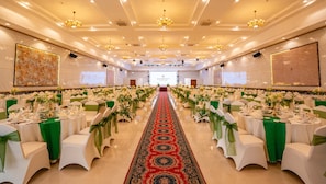 A banquet hall with rows of tables, green sashes, and chandeliers. - Van Phat Riverside Hotel (Can Tho)