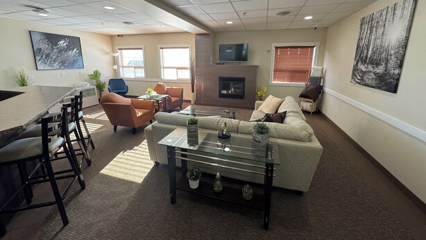 A modern living room with a dining area, a fireplace, and a large painting on the wall.