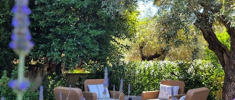 An outdoor seating area with wicker furniture and a stone floor.