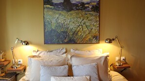 A hotel room with a bed, two bedside lamps, a painting on the wall, and a nightstand with a lamp and a basket. - Villa Agape in Kala Nera Pelion (South Pelion)