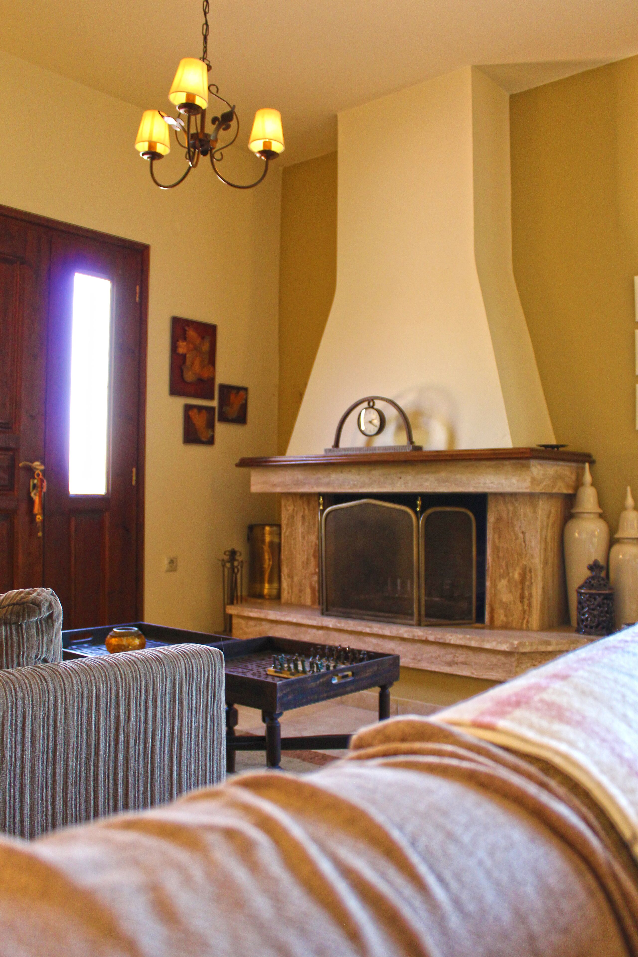 A cozy living room with a fireplace, a chandelier, and a door.