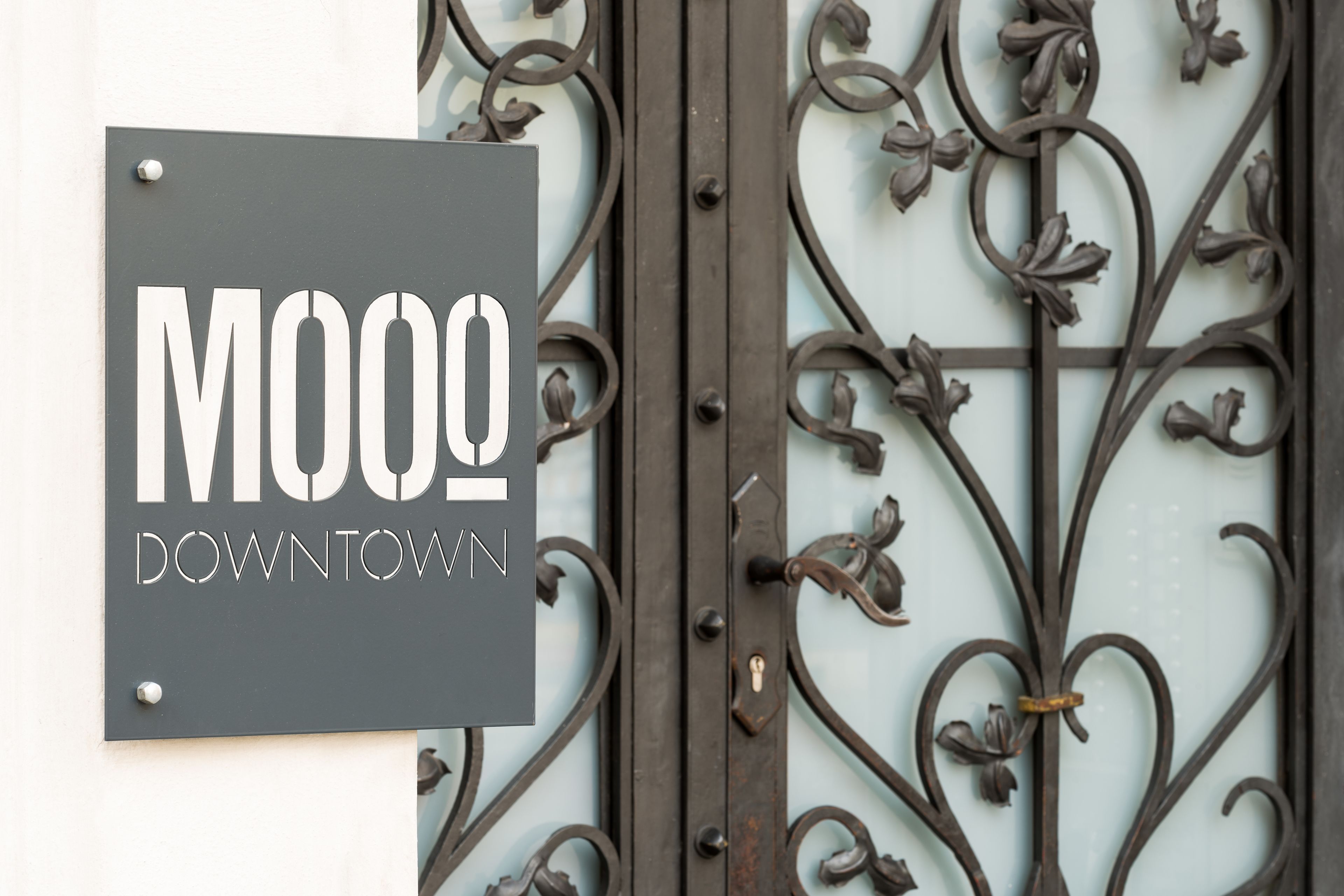Um letreiro com o texto 'MOOO DOWNTOWN' fixado em uma parede.