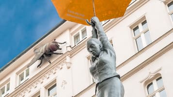 A statue of a person holding an umbrella in front of a building with ornate architectural details.