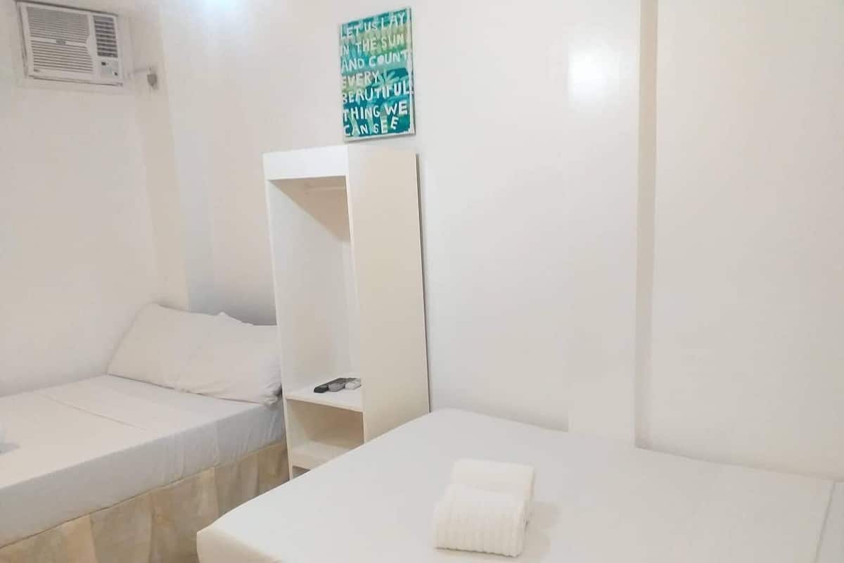 Ein Zimmer mit zwei Einzelbetten, einem weißen Kleiderschrank und einem kleinen Ablagefach für Toilettenartikel.