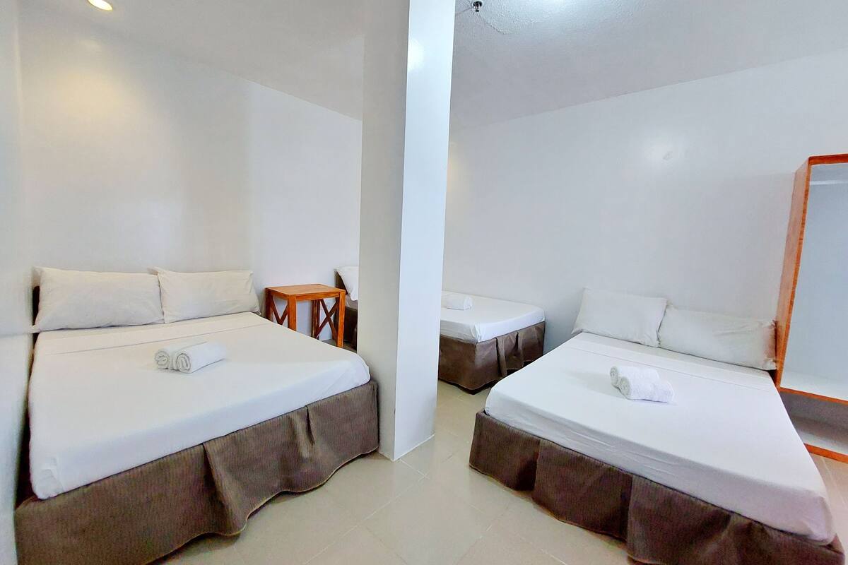 Ein Hotelzimmer mit zwei Betten, jeweils mit einem hölzernen Nachttisch und einem kleinen Tisch.