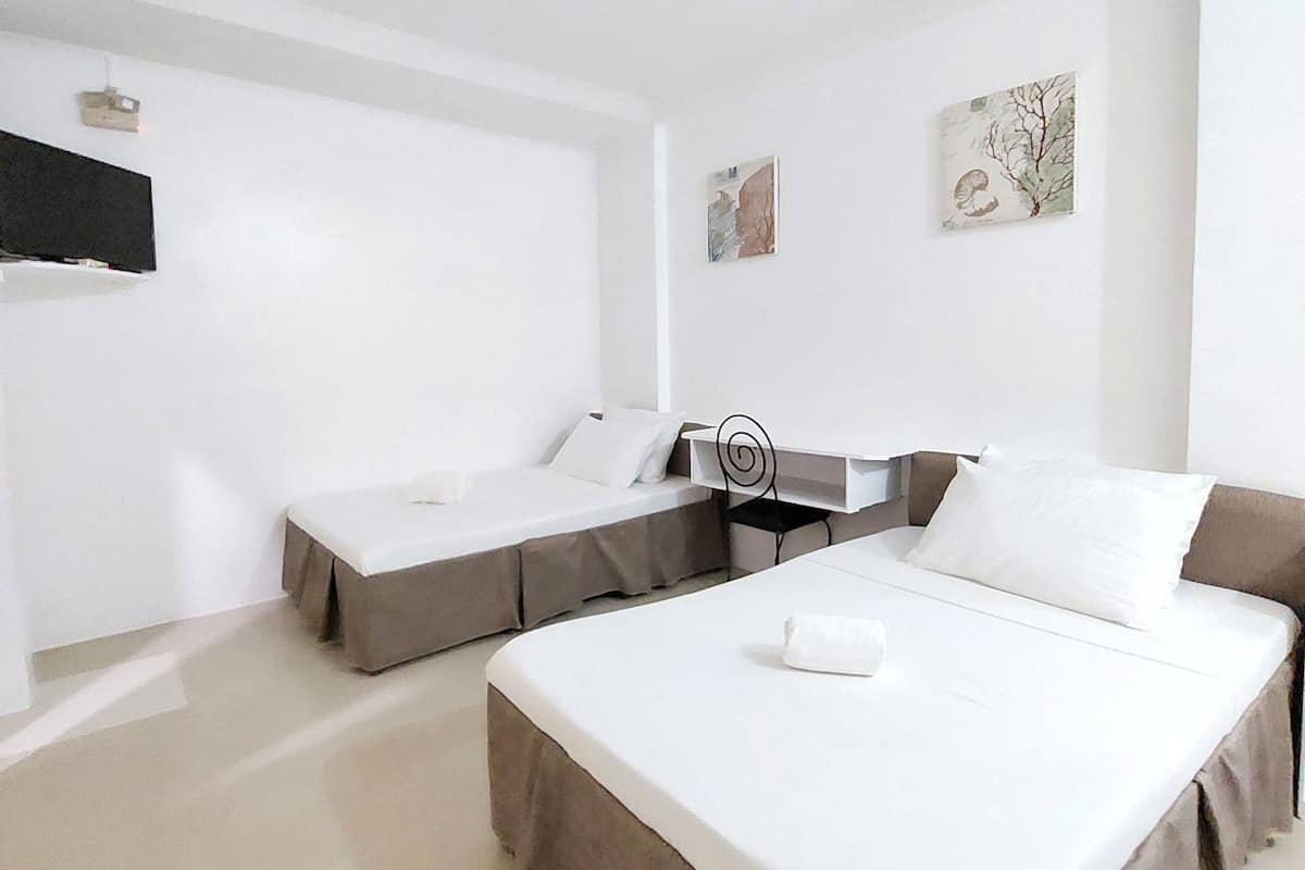 Ein Hotelzimmer mit zwei Betten, einem Schreibtisch und Bildern an den Wänden.