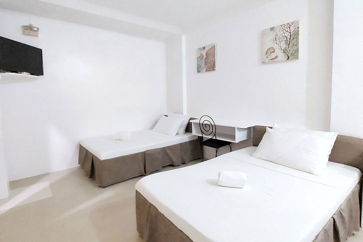 A hotel room with two beds, a desk, and artwork on the walls.